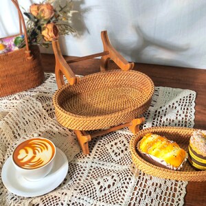 May include: Two woven rattan trays with wooden stands. The larger tray is on top of the smaller tray. The trays are empty.