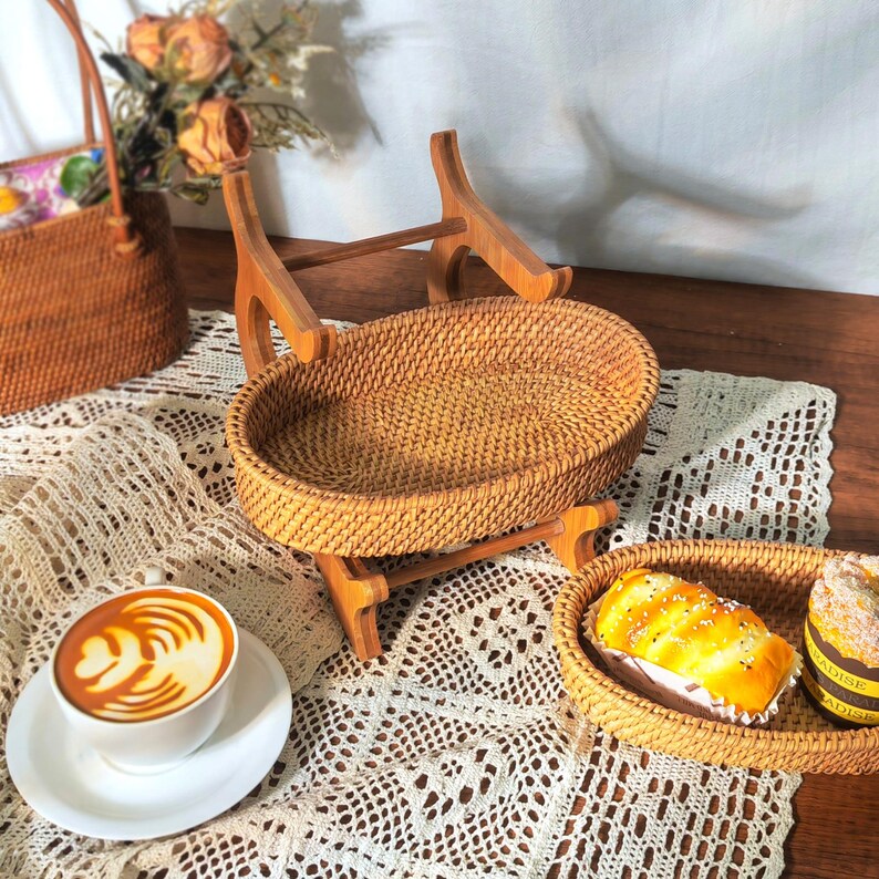 May include: Two woven rattan trays with wooden stands. The larger tray is on top of the smaller tray. The trays are empty.
