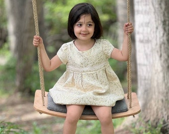 Handcrafted wooden swing hanging in a serene garden setting, inviting relaxation and tranquility