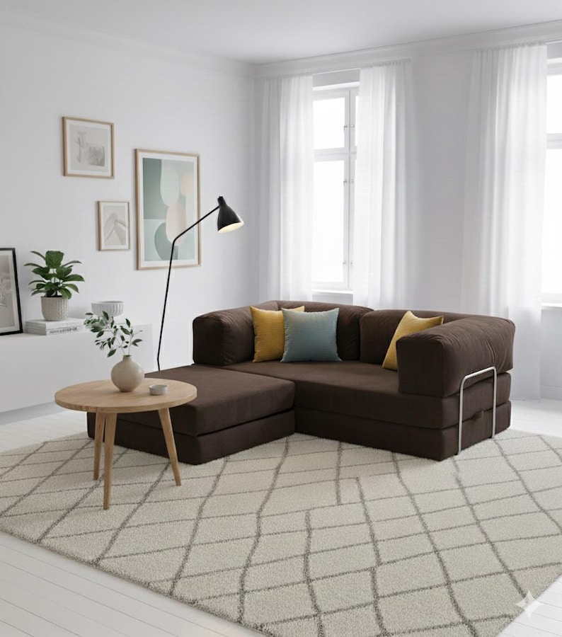 Puede incluir: Un sal&oacute;n moderno con un sof&aacute; seccional marr&oacute;n con cojines amarillos y azules. Una mesa de centro redonda de madera descansa sobre una alfombra estampada. Una l&aacute;mpara de pie negra y obras de arte enmarcadas completan el espacio.