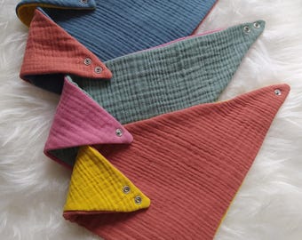 May include: Four triangular fabric bibs with snap closures. The bibs are reversible and feature a variety of colors, including yellow, blue, green, and red.
