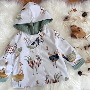 May include: White hooded jacket with a whimsical chicken print. The jacket features a green lining and cuffs, and is designed for children. The playful design includes various chicken illustrations in multiple colors.