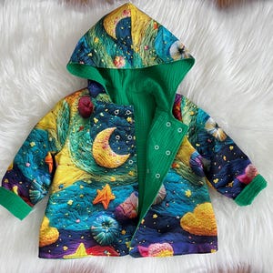 Könnte beinhalten: Bunte, gesteppte Babyjacke mit einem skurrilen Nachthimmel-Design. Die Jacke hat ein grünes Innenfutter und grüne Paspeln, mit einer lebendigen Außenseite, die einen Halbmond, Sterne und Wolken in Blau-, Gelb- und Lilatönen zeigt. Die Jacke hat eine Kapuze und Knopfverschlüsse.