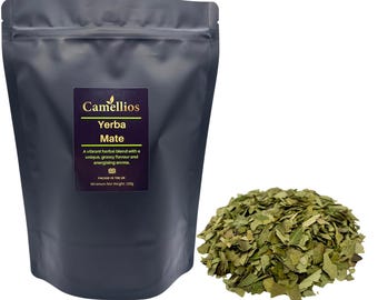 Könnte beinhalten: Ein dunkelgrauer Beutel mit Camellios Yerba Mate Tee mit einem Etikett, das die Kräutermischung beschreibt. Rechts befindet sich ein Haufen loser, getrockneter grüner Teeblätter. Auf dem Etikett steht, dass der Tee einen einzigartigen, grasigen Geschmack und ein anregendes Aroma hat.