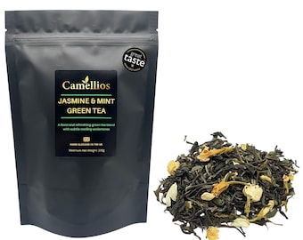 May include: A black pouch with a white label that reads "Camellios Jasmine & Mint Green Tea". The label also includes the text "A floral and refreshing green tea blend with subtle cooling undertones" and "Hand Blended in the UK". A gold star with the text "Great Taste" is on the top right corner of the pouch. A pile of loose leaf green tea with jasmine flowers is in the bottom right corner of the image.
