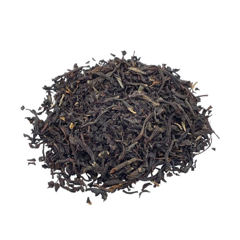 May include: A pile of loose leaf black tea, with a dark brown color and a slightly curled shape.