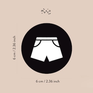 May include: Black and white illustration of a pair of shorts on a black circle. The circle is 6 cm in diameter.