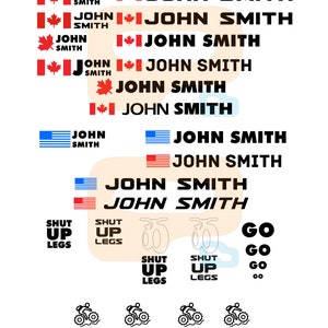 May include: A set of bike decals featuring various designs, including the text "JOHN SMITH" with Canadian and American flags, "SHUT UP LEGS", "GO", and "PUSH IT!" with bicycle illustrations.