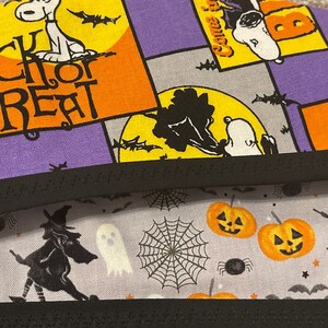 May include: Halloween-themed fabric with Snoopy and the words "Trick or Treat" in orange and black. The fabric also features pumpkins, witches, ghosts, and spiderwebs in orange, black, and white on a gray background.