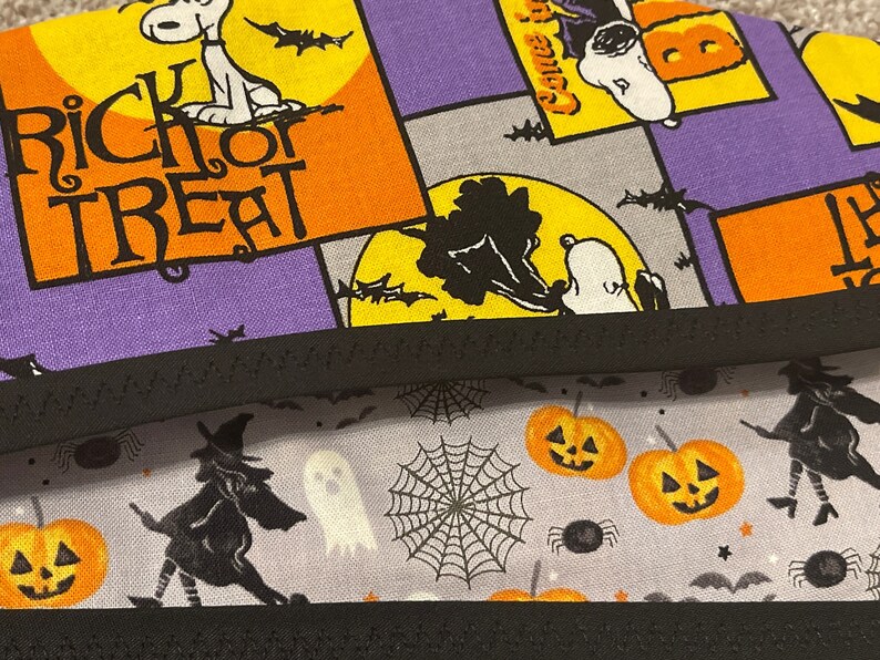 May include: Halloween-themed fabric with Snoopy and the words "Trick or Treat" in orange and black. The fabric also features pumpkins, witches, ghosts, and spiderwebs in orange, black, and white on a gray background.