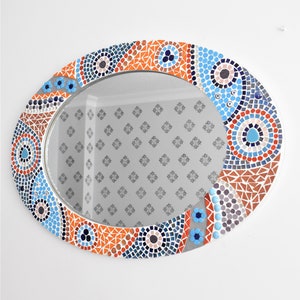 May include: Oval mirror with a mosaic frame in shades of blue, orange, and gray. The frame features geometric patterns and circular designs.