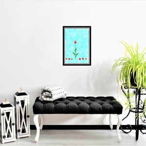 May include: A framed print of a red tulip with green leaves on a blue background. The print is hanging on a white wall above a black tufted bench.