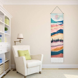 May include: A colorful abstract landscape wall tapestry with a watercolor style. The tapestry features a pink, orange, yellow, blue, and green color scheme with a white fringe at the bottom.