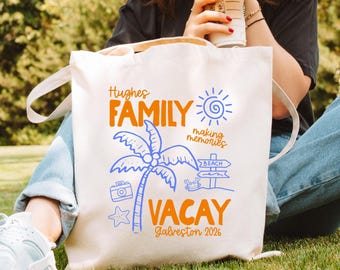 May include: A cream-colored canvas tote bag featuring a blue and orange graphic print that reads Hughes FAMILY making memories VACAY Galveston 2026, accompanied by illustrations of a palm tree, a sun, a camera, a starfish, a crab, and a beach sign.