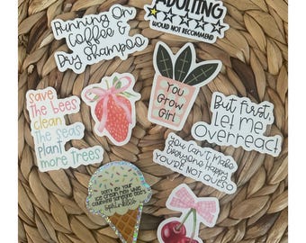 May include: A collection of seven vinyl stickers featuring various designs and text, including a strawberry with a pink bow, a potted plant, an ice cream cone with sprinkles, cherries with a pink bow, and phrases like Adulting Would Not Recommend.
