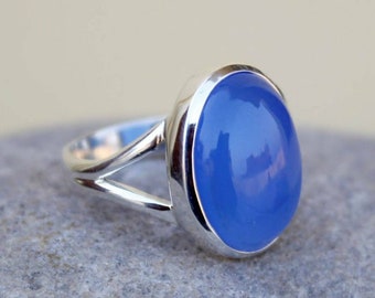 May include: A silver ring with a light blue oval gemstone. The ring has a simple design with a split band.