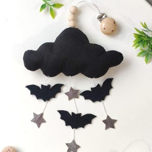 May include: Black felt cloud mobile with hanging bats and silver stars. The cloud is attached to a wooden ring with a clip for hanging.