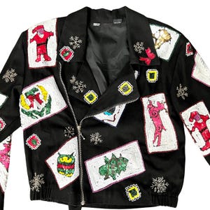 May include: A black zippered jacket with a festive holiday theme. The jacket is covered in colorful sequins and features various holiday-themed designs, including Santa Claus, snowflakes, and Christmas trees.