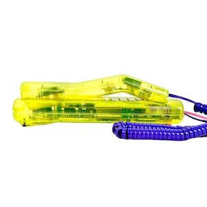 May include: A vintage yellow Swatch telephone with a coiled purple cord. The phone's transparent plastic casing reveals internal components. The handset is curved and rests on the base. A pink and blue wire connects the handset to the purple cord.