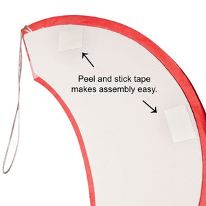 May include: A curved, white piece with a red border and two peel-and-stick tape squares. The text "Peel and stick tape makes assembly easy" is printed on the white surface. A thin, silver wire is attached to the top.