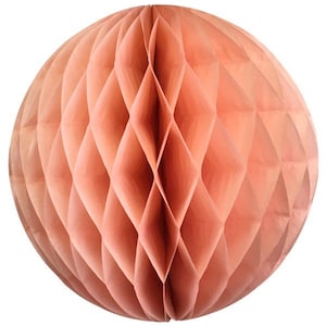 May include: A peach-colored, spherical paper honeycomb decoration. The ball is made of folded paper, creating a geometric diamond pattern across its surface. The paper has a matte finish and a warm, inviting tone, suitable for party or event decor.