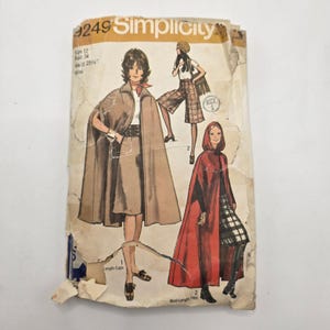 May include: A vintage Simplicity 9249 sewing pattern envelope for size 12, bust 34, waist 25.5 inches. The front features illustrations of a tan cape, plaid culottes, and a red hooded maxi-length cape, with visible wear and paper creasing.