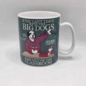 May include: White ceramic mug with a humorous design. The mug features a cartoon dog dressed as a teacher, pointing to text that reads "If you can't teach with the big dogs, stay out of the classroom."