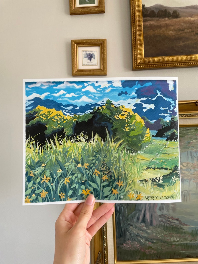 May include: A painting depicting a landscape with a field of yellow flowers in the foreground, green trees and hills in the middle ground, and a blue sky with white clouds in the background. The painting is signed "Rosemilkcook" in the bottom right corner.