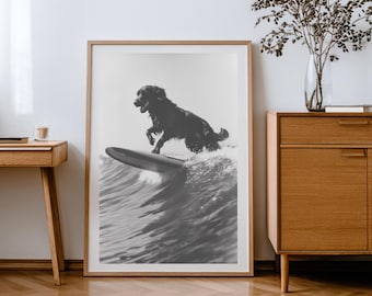 Puede incluir: Impresión enmarcada en blanco y negro de un perro surfeando una ola. El perro está en el aire, equilibrándose sobre una tabla de surf, con agua salpicando. La impresión está en un marco de madera.