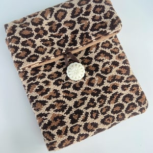 May include: A small brown and tan leopard print fabric pouch with a white button closure.