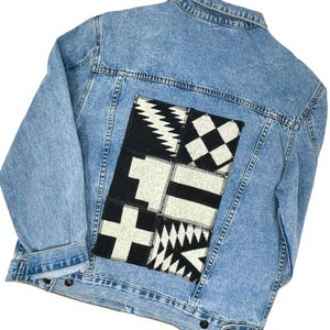 Puede incluir: Una chaqueta vaquera azul con un parche estampado en blanco y negro en la espalda.