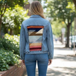 Puede incluir: Chaqueta vaquera azul claro con un diseño geométrico colorido en la espalda. La chaqueta se combina con vaqueros azules a juego y zapatillas blancas. El diseño de la parte trasera de la chaqueta presenta una mezcla de colores como naranja, azul y rosa.
