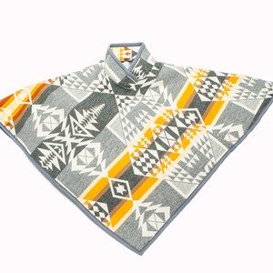 May include: A grey, white and yellow patterned poncho with a grey trim. The poncho has a geometric design with a Native American inspired pattern.