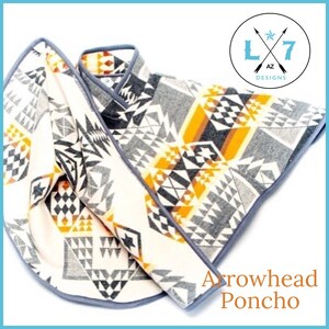 May include: A white, grey and orange patterned poncho with a grey trim. The poncho is folded in half and the text "Arrowhead Poncho" is visible below. The logo "L7 AZ Designs" is in the top right corner.