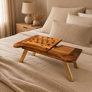 May include: A wooden laptop desk with foldable legs and a ventilated surface featuring multiple circular cutouts. The desk includes a flat side section with a circular indentation for a cup and a tilting platform for a laptop or book.