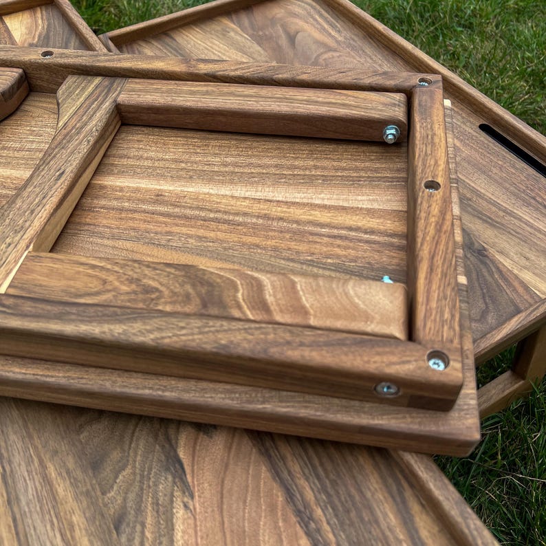 May include: A set of three wooden trays with a natural wood finish. The trays are made of solid wood and have a simple, elegant design. The trays are nested together, with the largest tray on the bottom and the smallest tray on top.