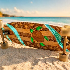 Könnte beinhalten: Ein Longboard aus Holz mit einem Schildkröten-Design und türkisfarbenen Akzenten liegt an einem Sandstrand. Das Board hat ein geometrisches Muster und grüne Schildkröteneinsätze. Die Rollen sind durchscheinend beige.
