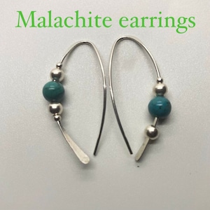 Puede incluir: Un par de pendientes de aro de plata con una cuenta de piedra preciosa verde turquesa y dos cuentas de plata en cada pendiente.