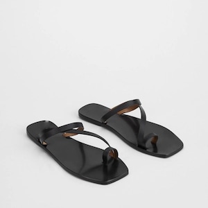 May include: A pair of black leather sandals with a square toe design. The sandals feature a toe loop and thin straps. The footwear is displayed on a white background.