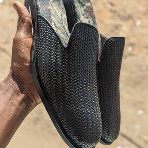 May include: A pair of black woven leather slip-on shoes with a patterned fabric lining.