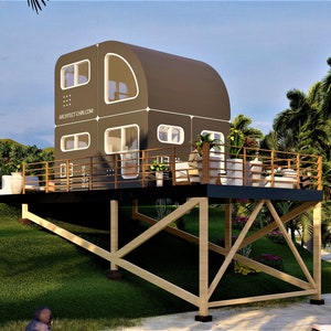 May include: A modern, dark brown, rounded, modular home with large windows sits on a wooden platform with a railing. The home is elevated on wooden stilts and is surrounded by palm trees and green grass.