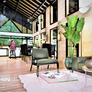 May include: A modern living room with a large window overlooking a green forest. The room features a green sofa, a glass coffee table, a green armchair, and a pink rug. The room is decorated with plants and a black and white print on the coffee table.