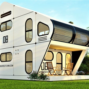 May include: A white, modern, modular home with a curved roof and large windows. The home has a small patio with two chairs and a table. The home is surrounded by green grass and trees.