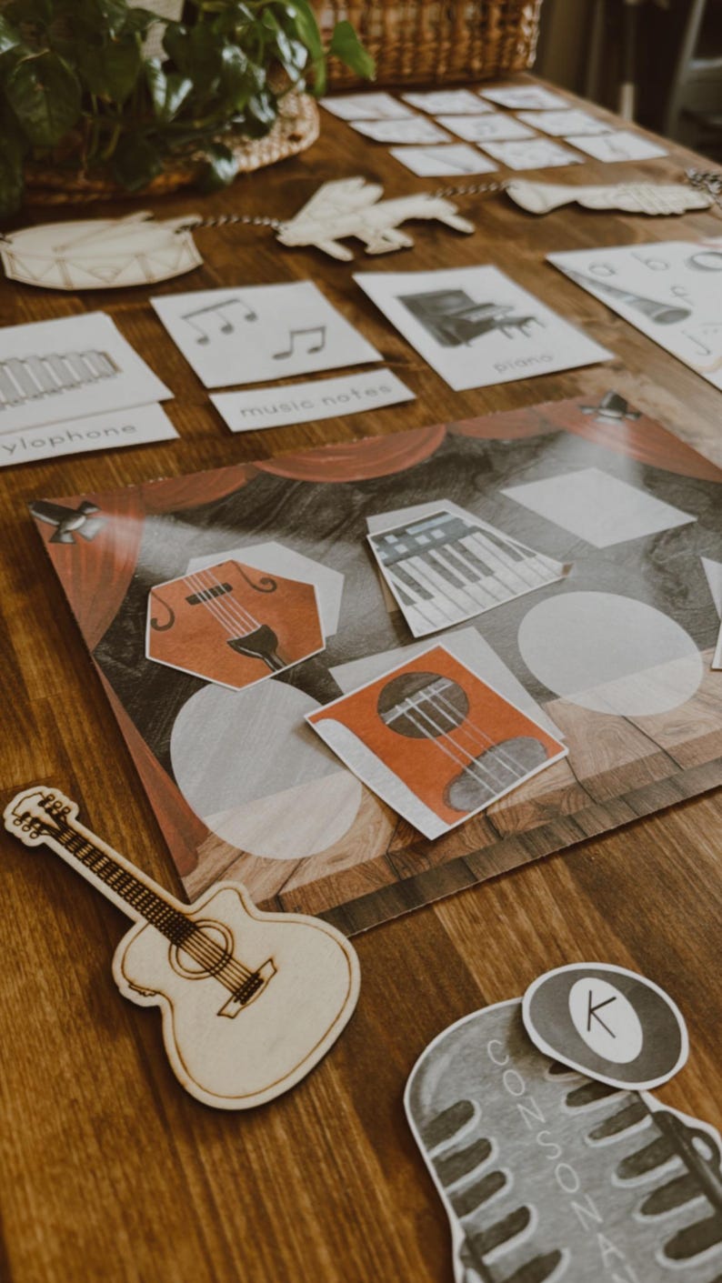 Pu&ograve; includere: Chitarra in legno e varie flashcard a tema musicale su una superficie di legno. Le flashcard includono note musicali, un pianoforte, uno xilofono e un microfono. L'immagine ha un'estetica calda, ideale per materiali didattici.