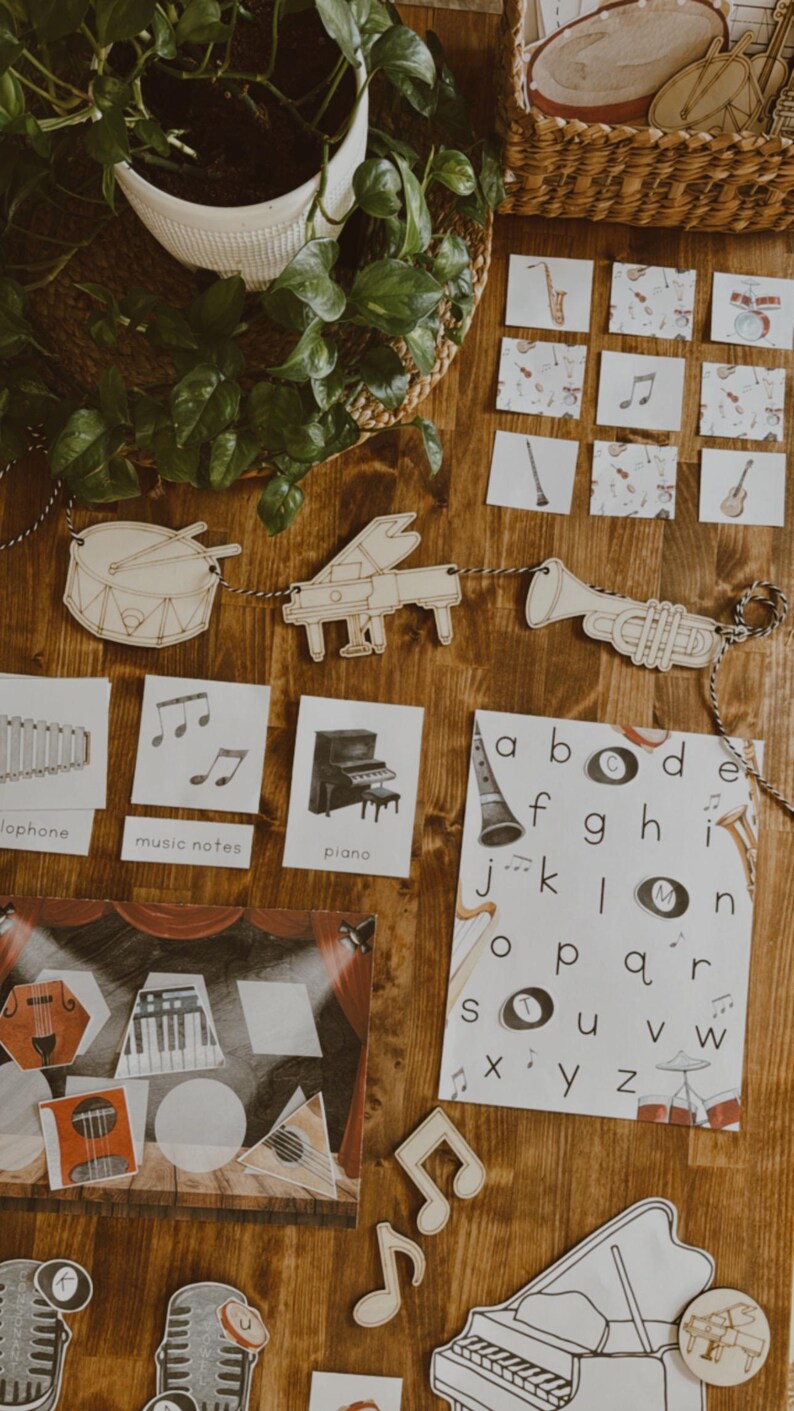 Pu&ograve; includere: Sagome di strumenti musicali in legno e flashcard con note musicali, un pianoforte e una tromba. Uno striscione di strumenti musicali in legno &egrave; appeso sopra le flashcard. &Egrave; visibile anche un poster con l'alfabeto.