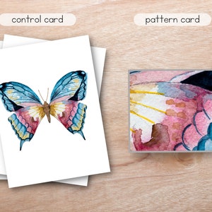 May include: A watercolor painting of a butterfly with blue, pink, and yellow wings. The butterfly is on a white background. The image is a control card for a pattern.