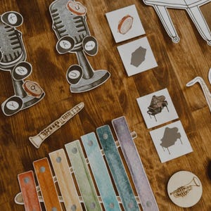 Pu&ograve; includere: Una collezione di ritagli di strumenti musicali, tra cui uno xilofono, un microfono, un pianoforte e una chitarra, disposti su una superficie di legno. Gli strumenti sono raffigurati in uno stile acquerello con una variet&agrave; di colori.