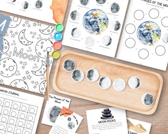 Pode incluir: Materiais educativos para aprender sobre as fases da lua. Inclui páginas para colorir com a palavra "Moon", um diário e atividades de recortar e colar. Uma bandeja de madeira contém recortes das fases da lua. Tintas aquarela e um pincel também estão presentes.