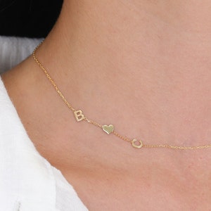 May include: A gold chain necklace with a heart charm and two letter charms, one 'B' and one 'C'.