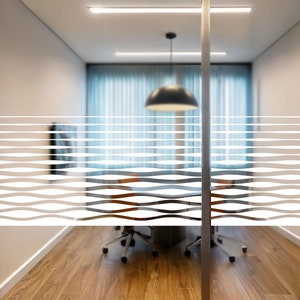 May include: A frosted glass door with a white wavy line pattern. The door is in a modern office setting with a wooden floor and a table with chairs.